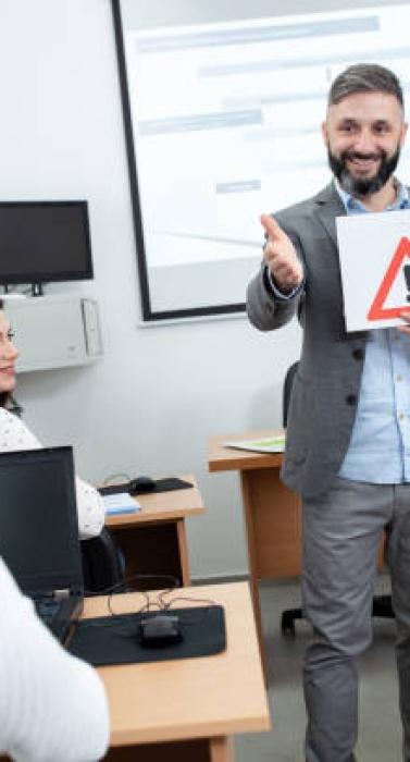 Driving instructor asking students about the traffic sign he is holding in the classroom